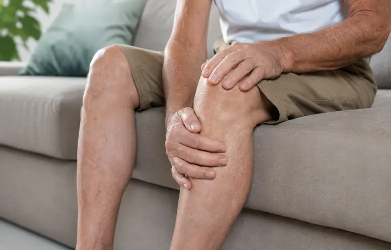 Persona mayor sentada sujetándose la rodilla como símbolo de movilidad y cuidado corporal